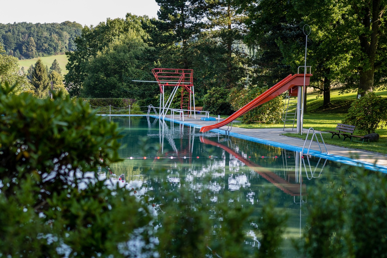 Waldbad: Schwimmbecken mit Sprungturm und Rutsche