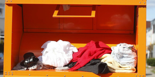Einwurföffnung eines Sammelcontainers mit Kleidungsstücken