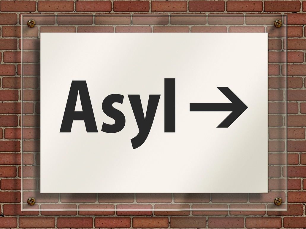 Neuer Betreiber für Asylunterkunft in Hoyerswerda an einer Ziegelwand hängt ein Schild mit dem Aufdruck "Asyl", ein Pfeil weist nach rechts