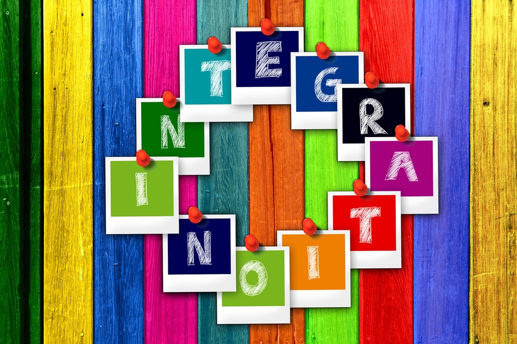 Symboilbild: Eine Wand aus bunten Holzlatten, darauf Bilder mit dem Schriftzug Integration