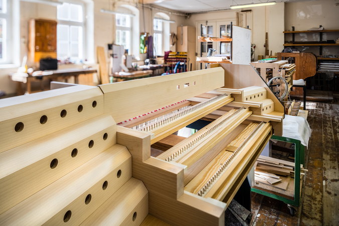 Blick in die Werkstatt der Firma Orgelbau Eule in Bautzen In einer Werkstatt liegen vorgefertigte längliche Teile aus Holz.