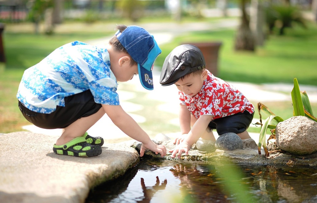 zwei kleine Kinder spielen an einer Wasserrinne