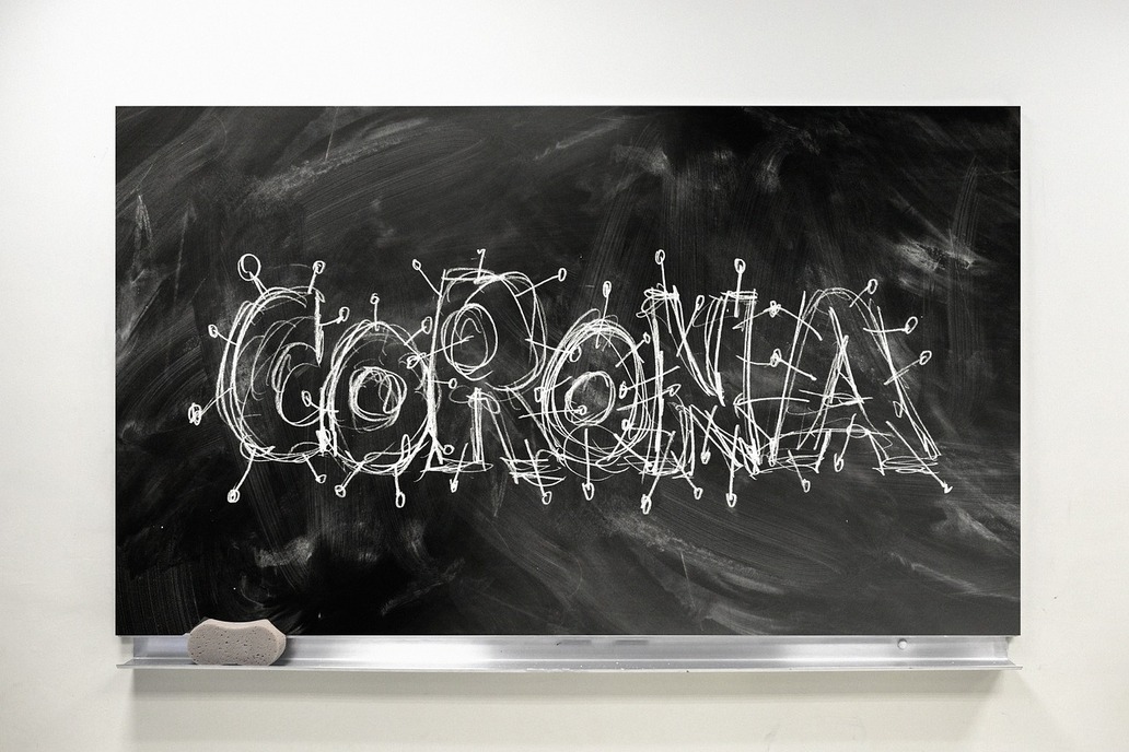 Corona und Schule eine Schultafel, auf der der mit Kreide geschriebene Schriftzug 'Corona' zu sehen ist.