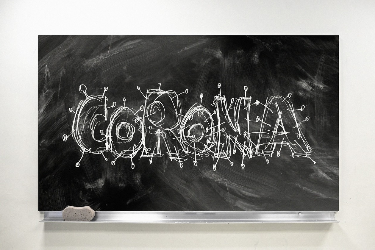 eine Schultafel, auf der der mit Kreide geschriebene Schriftzug 'Corona' zu sehen ist.