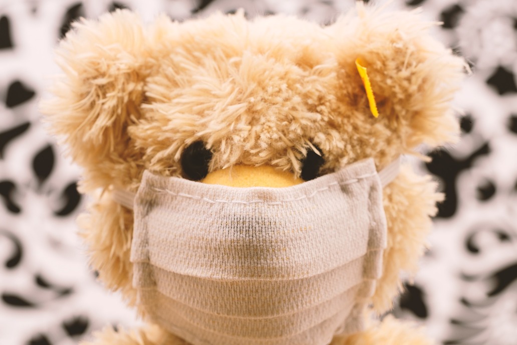 Covid 19 in der Kita der Kopf eines Teddybären mit Mund-Nasenschutz