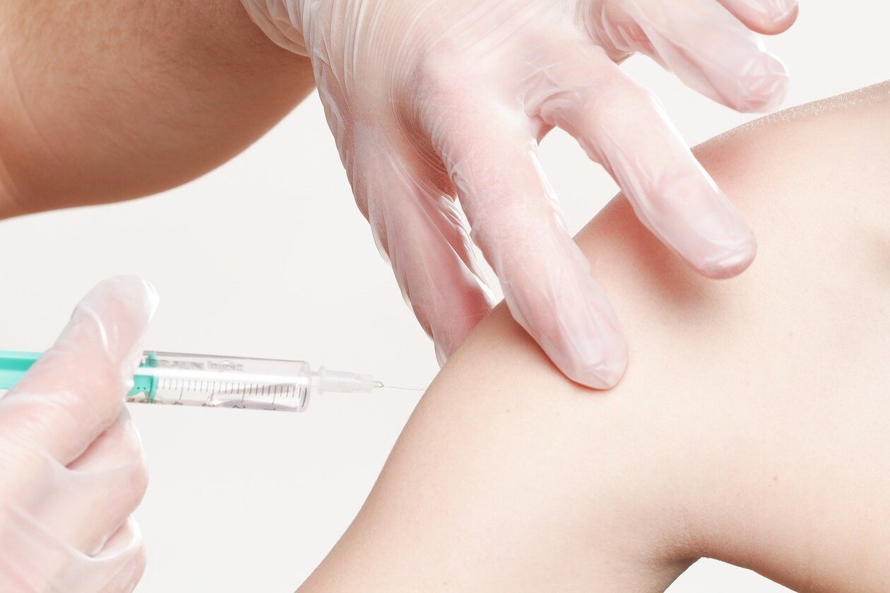 in den Oberarm eines Menschen wird die Nadel für eine Injektion angesetzt