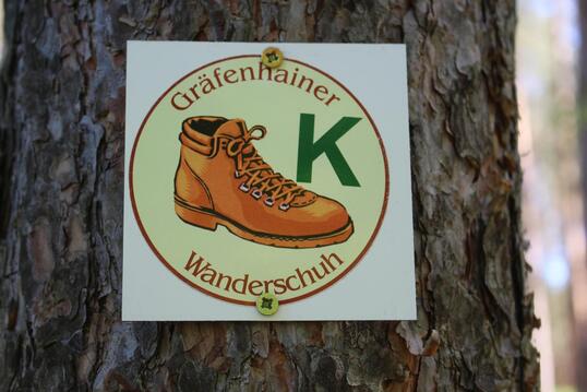 Logo des Wanderweges: Ein Wandershcuh mit dem Buchstaben "K" und der Namen des Weges "Gräfenhainer Wanderschuh"
