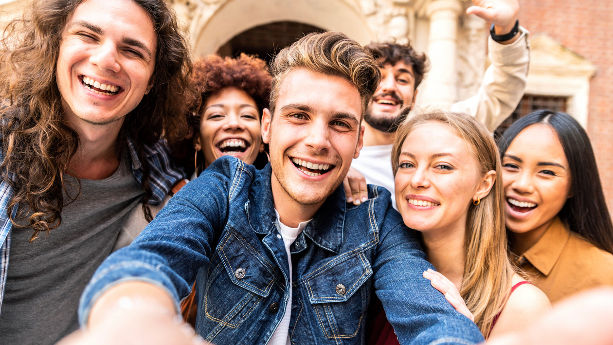 drei junge Männer und drei junge Frauen lachen in eine Kamera