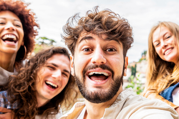 drei junge Frauen und ein junger Mann lachen 