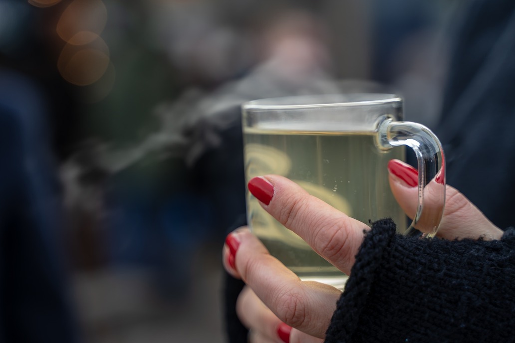 Eine Frauenhand hält ein Glas Glühwein.