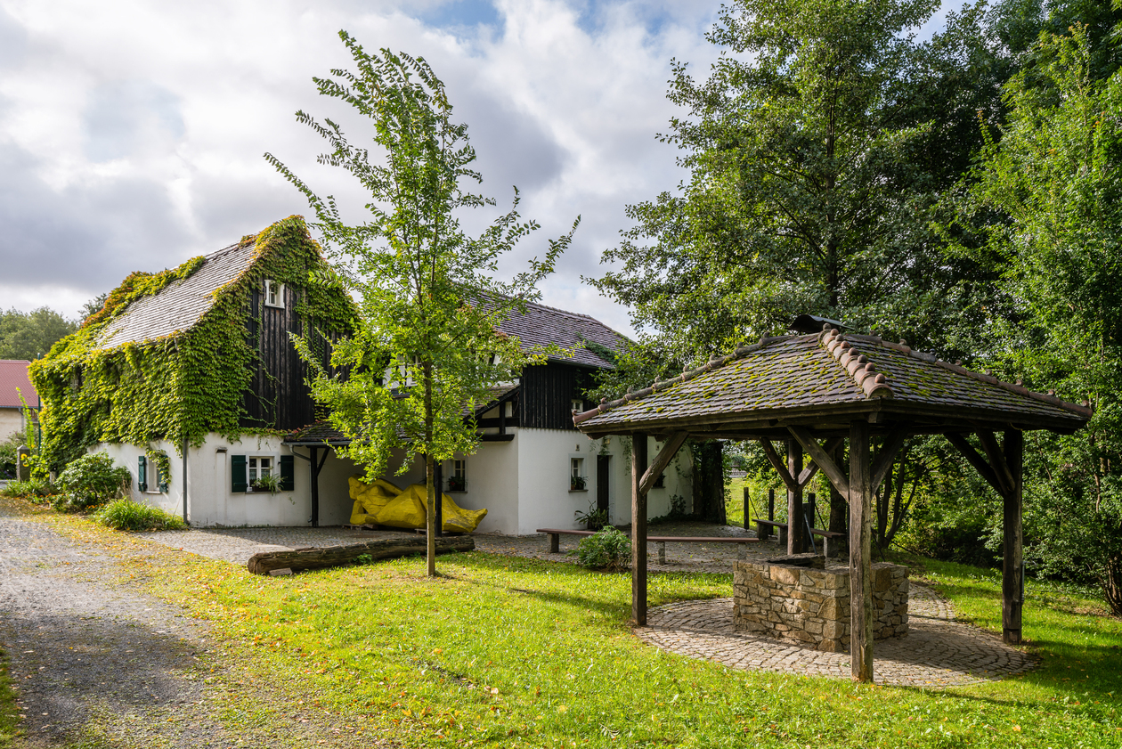 Historisches Ensemble eines Hofes: Haus mit Nebenhaus und Brunnenanlage und Bäiumen