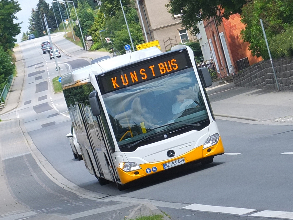 Kunstorte in der Region mit dem Bus erkunden Ein Bus mit der Anzeige Kunstbus fährt durch eine Ortschaft