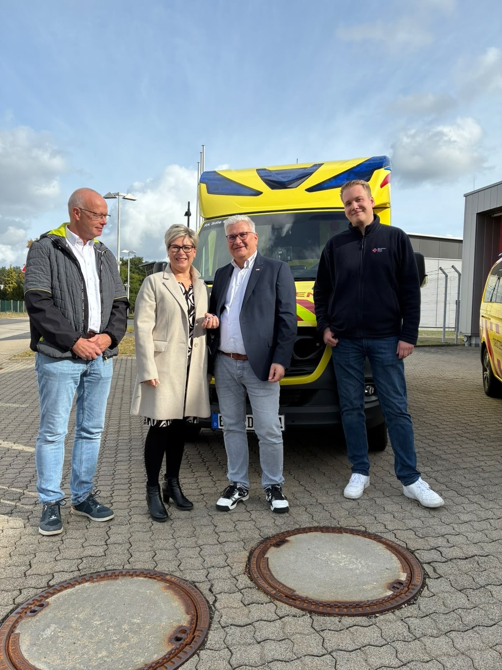 drei Männer und eine Frau vor einem Rettungswagen