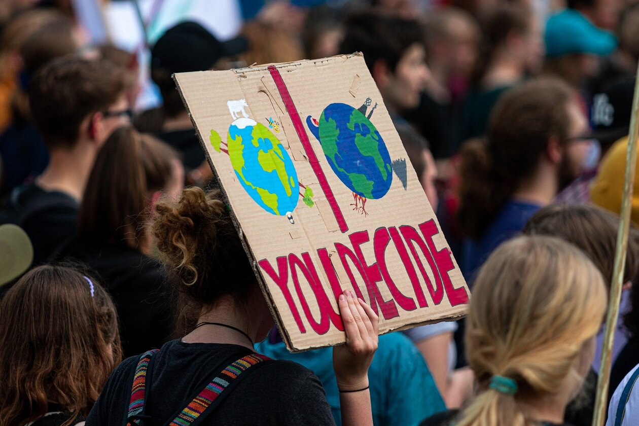 Eine Menschengruppe, ein Schild mit einer bunten Aufschrift wird hoch gehalten.