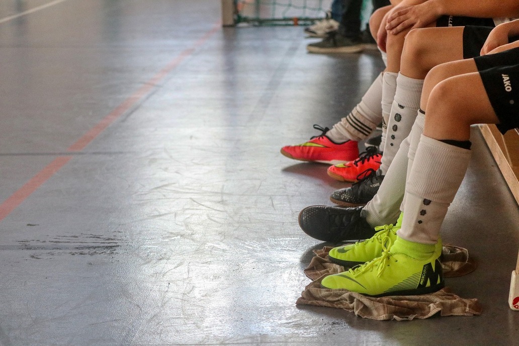 Boden einer Turnhalle,Beine von Kindern, dei Fußballschuhe tragen