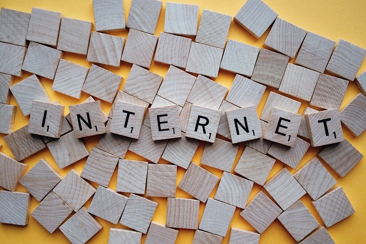 viele Holzbausteine quadratisch angeordnet. In der Mitte sind Bausteine umgedreht, die jeweils einen schwarzen Buchstaben in der Mitte haben und das Wort Internet ergeben. Ähnlich das Bild eines Scrabble-Spieles