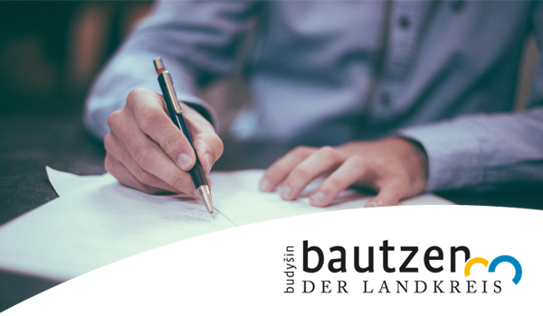 Mann mit Stift unterschreibt Arbeitsvertrag