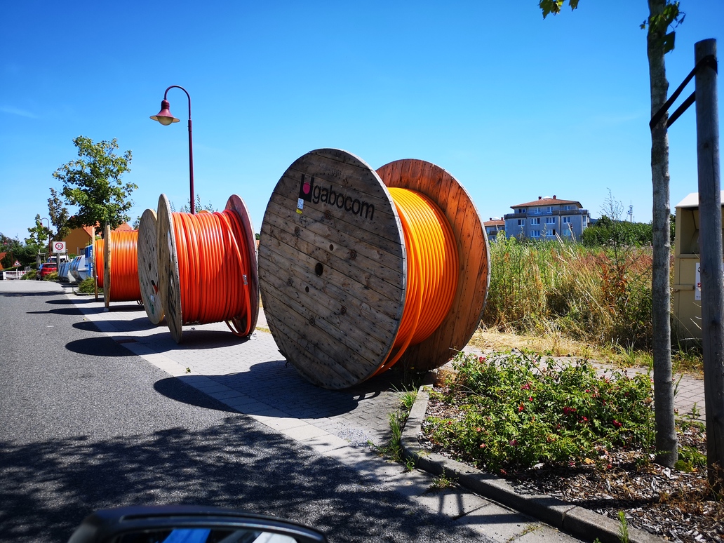 Kabeltrommlen mit Glasfaserkabel, die am Straßenrand liegen