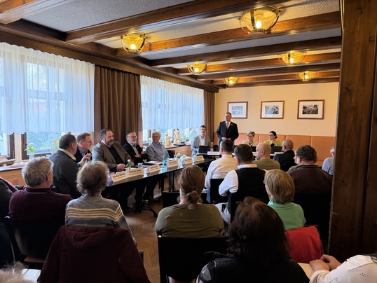 Mehrere Personen sitzen in einem Raum, im Präsidium 6 Männer und drei Frauen