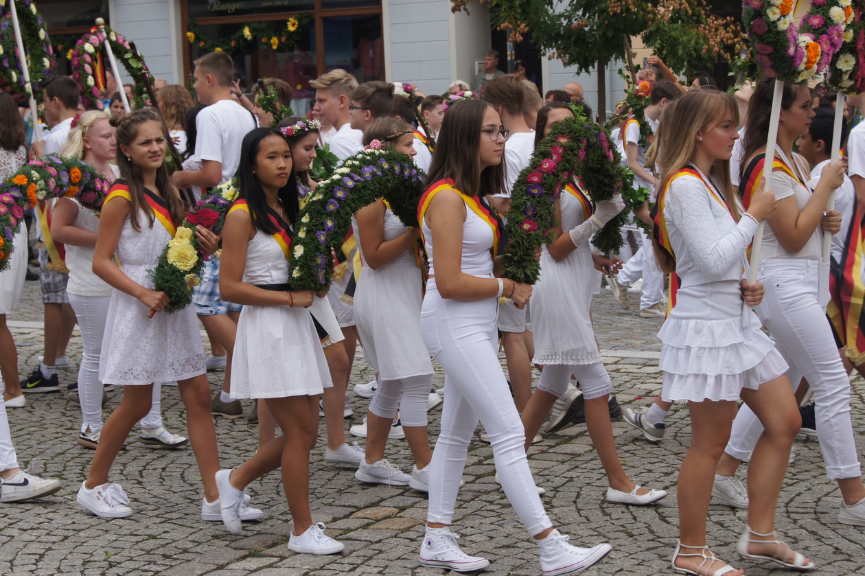 Junge Mädchen in weißer Kleidung tragen Blumengebinde