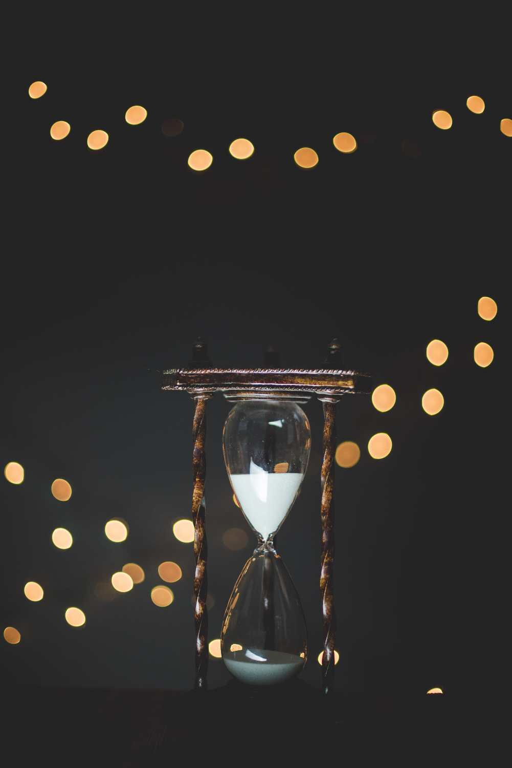 eine Sanduhr, im Hintergrund funkelnde Lichtreflexe