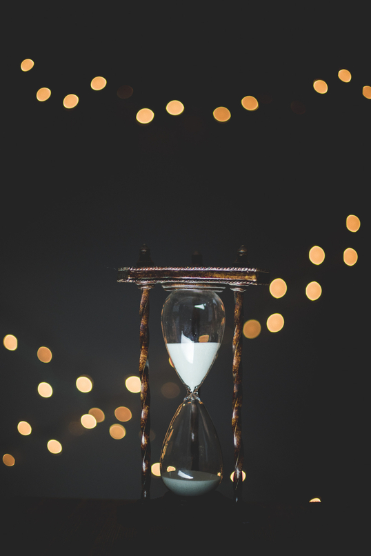 eine Sanduhr, im Hintergrund funkelnde Lichtreflexe