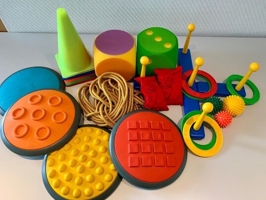 Auf dem Bild sind Bälle, Springseile, Kegel, Würfel und Fußmatten mit verschiedenen Oberflächen zu sehen